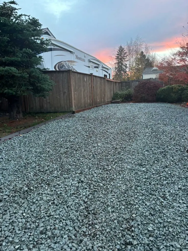Freshly installed gravel pad in a residential backyard, ideal for parking or landscaping projects.