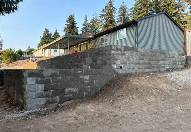 Large concrete block retaining wall built on a sloped residential property.