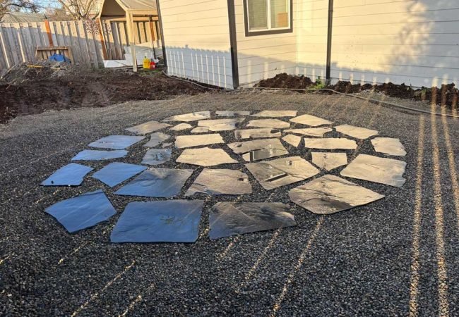 Circular flagstone patio set in gravel base in a residential backyard.